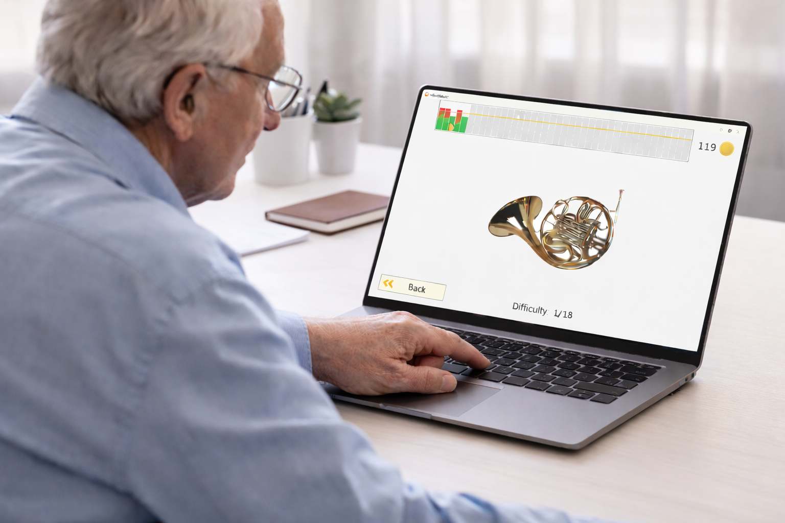 Elderly patient using HeadApp Hit It reaction training on a laptop